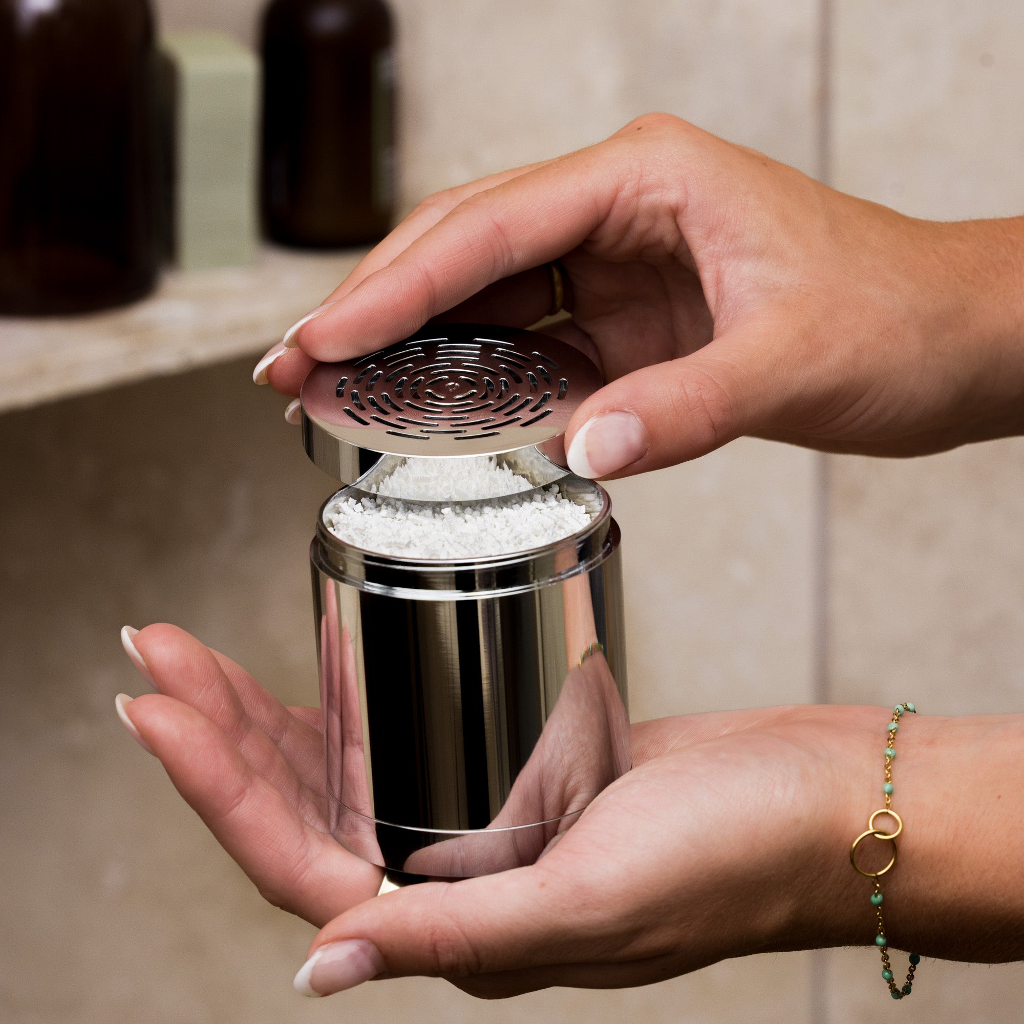 Person holding a metallic salt grinder with a textured top
