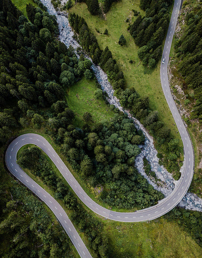 Aerial shot of a meandering road through a mountain forest