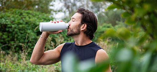 A woman drinking from her black Tritan Water Bottle