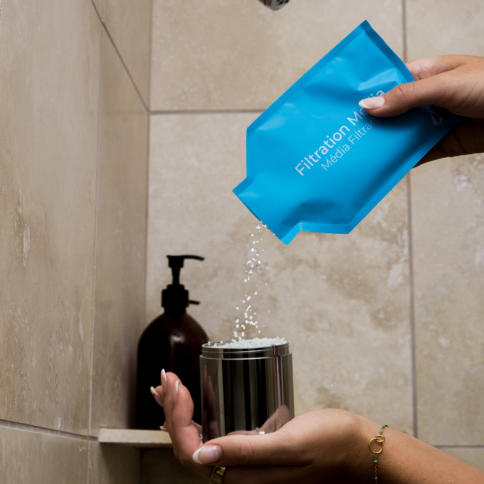 Person holding a blue filtration media filter over a shower head with water flowing.