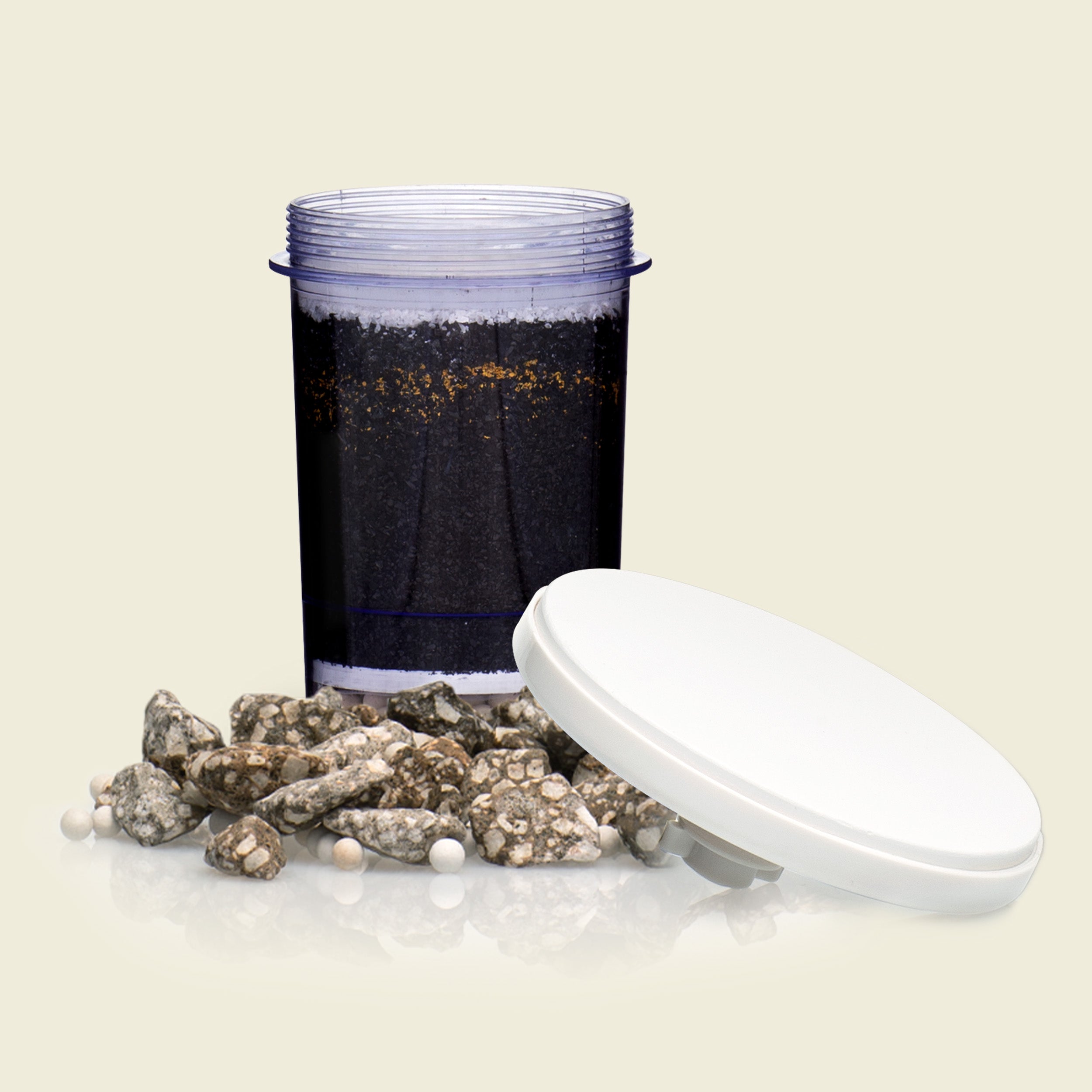 Container with soil and small rocks on a beige background