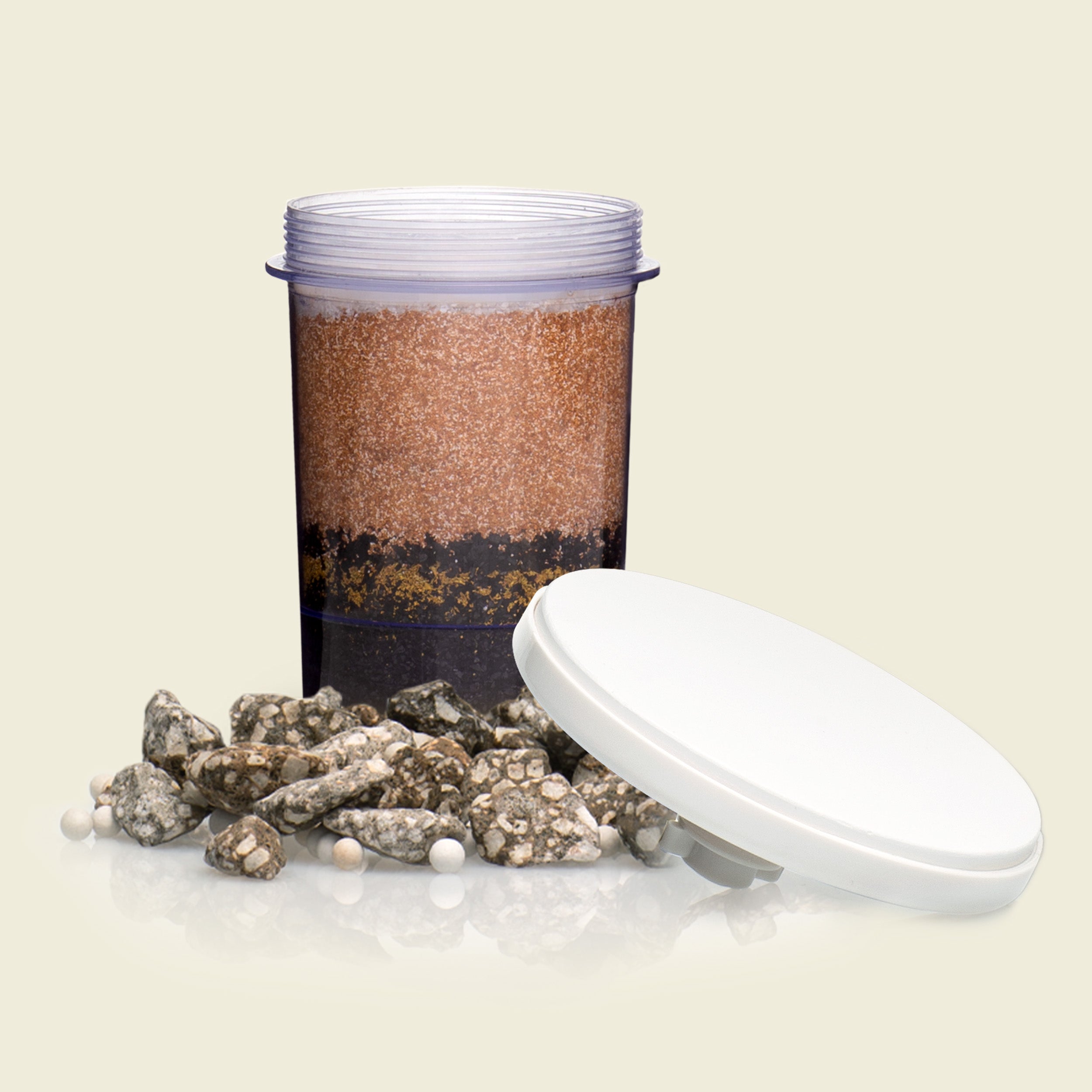 Container with layered material and rocks on a beige background