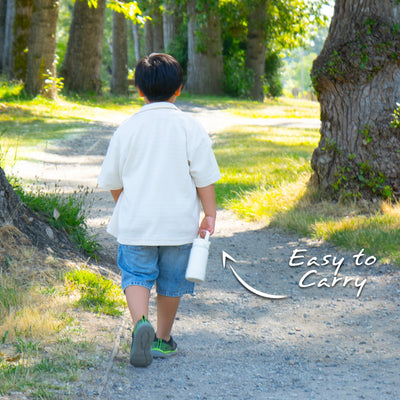 Santevia Kids Bottle Ivory held by child walking down forested park path. Easy to carry