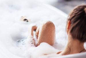 A woman enjoying a bubble bath with her Santevia Bath Filter