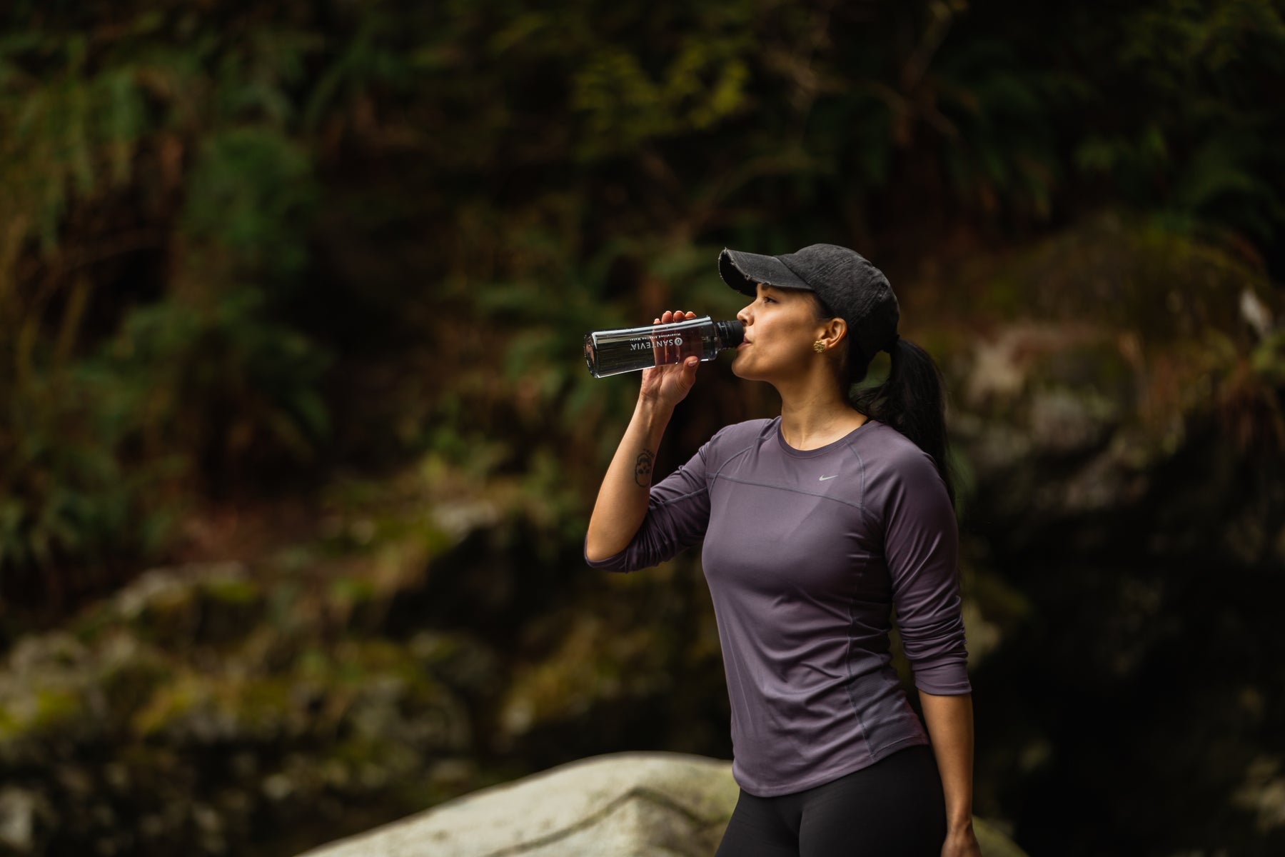 A woman on a hike drinking from a Santevia Tritan Water Bottle