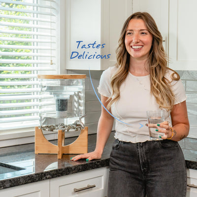 Women smiling in a kitchen drinking a glass of mineral water from the Santevia Glass Water System#filtration-type_standard