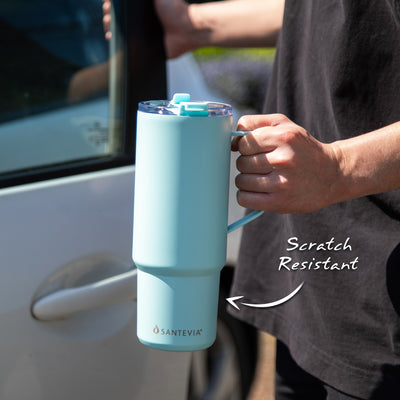 Santevia 900 mL glacier tumbler being held by someone getting into a car on a sunny day - are scratch resistant - glacier blue