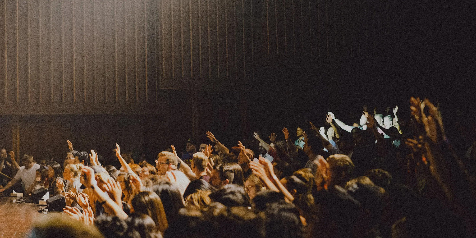 An auditorium full of people raising their hands to speak